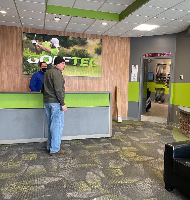 Man Standing in Front of a Golf Tec Sign — Scottsville, NY — Eljon Enterprises LLC