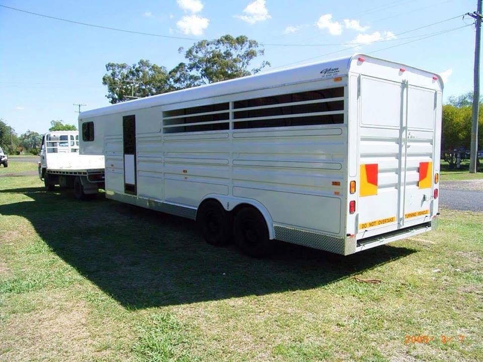 A large white trailer is parked in a grassy field