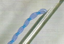 A close up of a needle with a blue thread coming out of it.