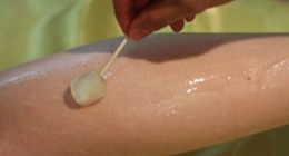 A person is applying wax to a woman 's leg with a cotton swab.