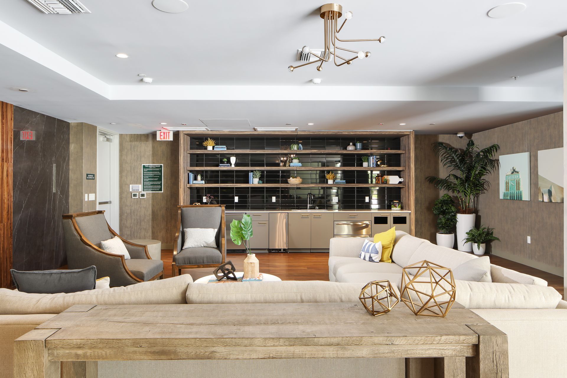 Modern living room with beige sofas, wood shelving, and neutral decor around a wall-mounted TV.