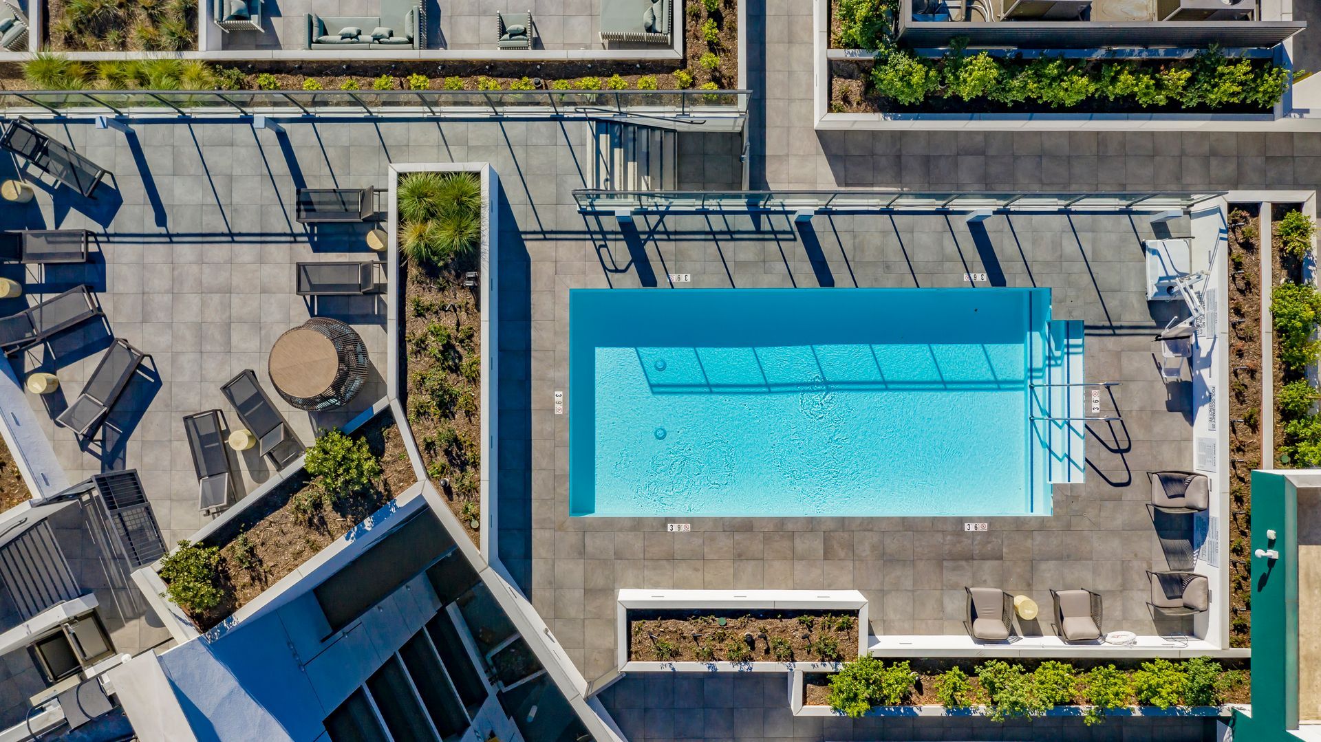 Aerial view of a rooftop pool surrounded by lounge chairs and city buildings.