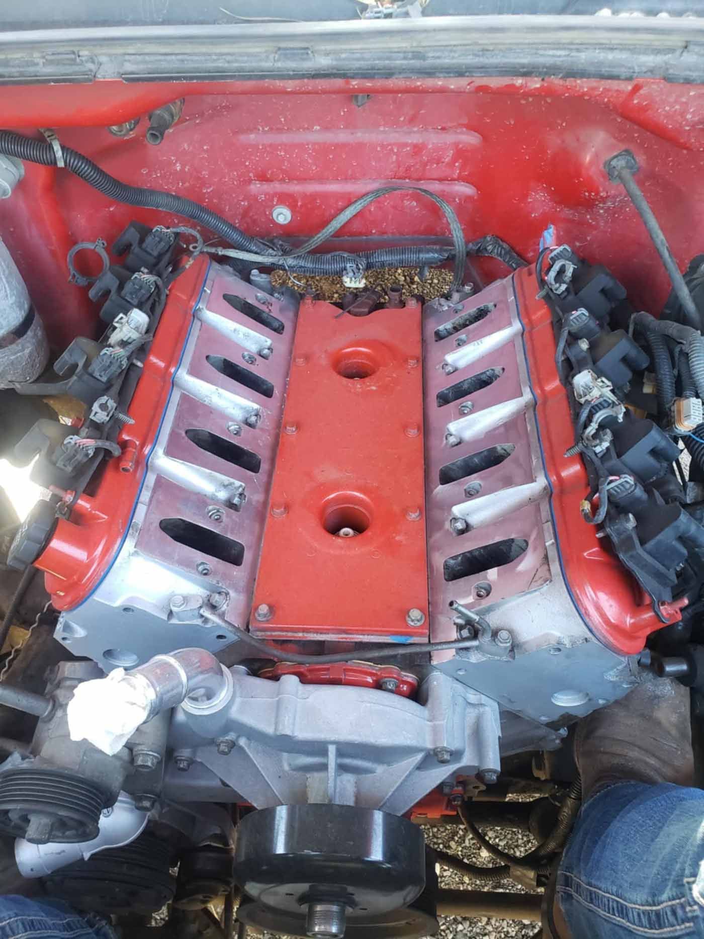 Red engine block with silver valve covers and red painted covers. Wiring and other components are visible, likely in an automotive setting.