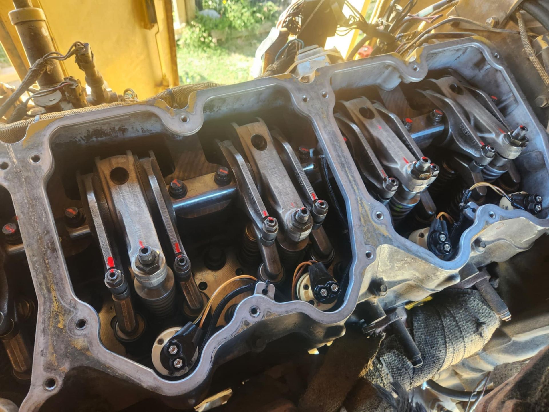 Engine component with exposed valves, pushrods, and rocker arms inside a yellow machine.