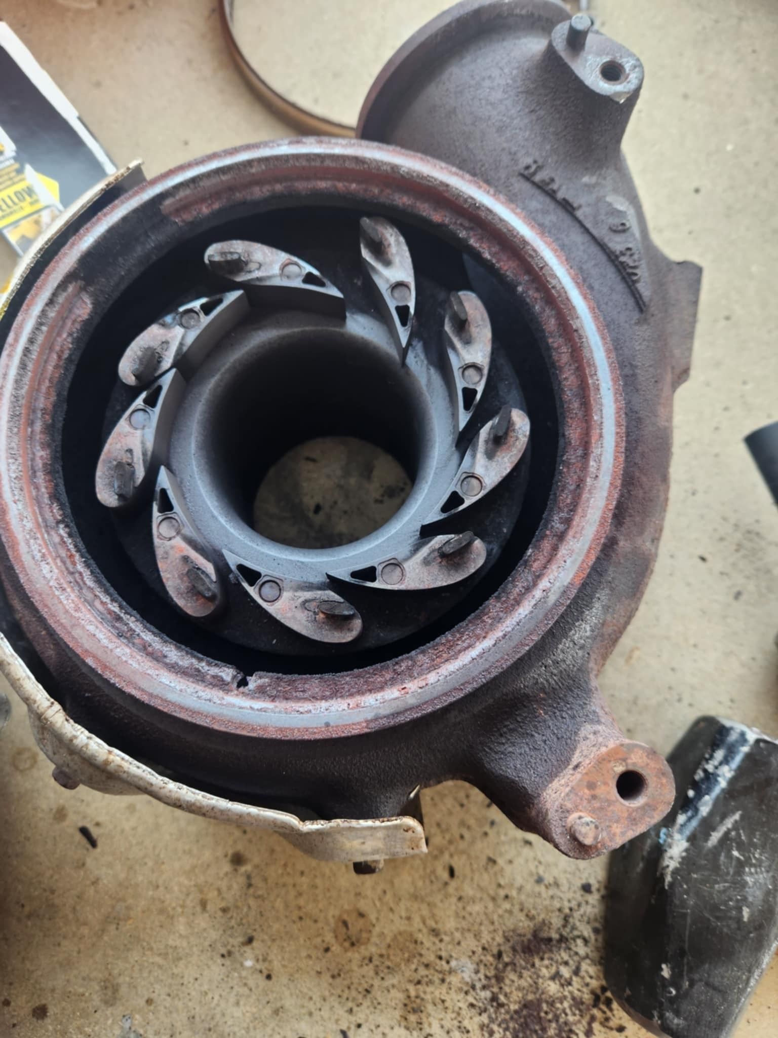 Close-up of a damaged turbocharger turbine wheel, showing worn blades and a rusty housing.