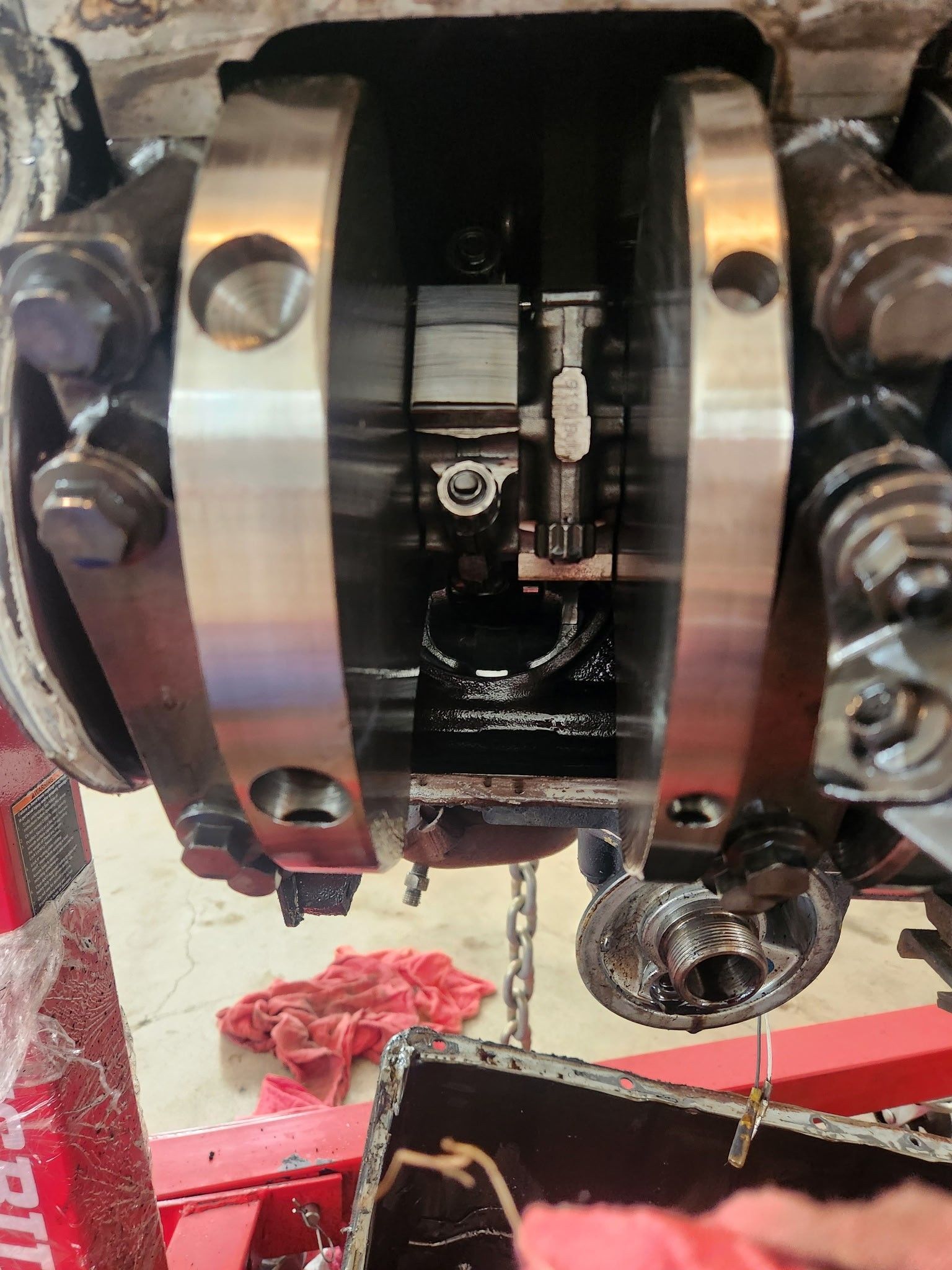 An engine's open crankcase with visible crankshaft and bearing caps.  Black oil coats components.