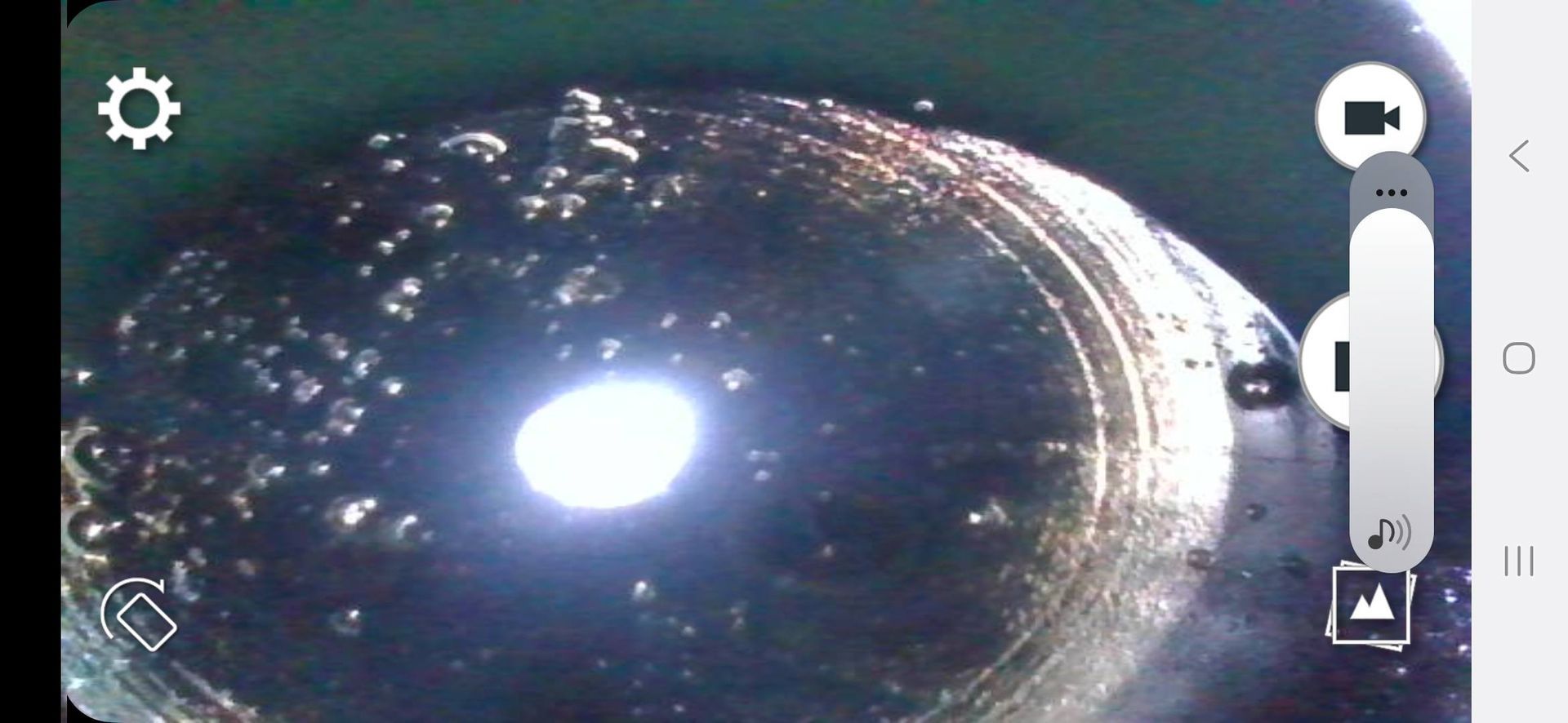 A close-up of a surface with light reflecting, surrounded by camera controls. The view appears to be from a device.
