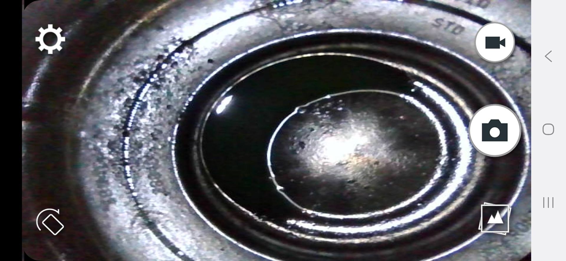 View inside an engine cylinder with dark liquid. The cylinder walls show wear and the markings 