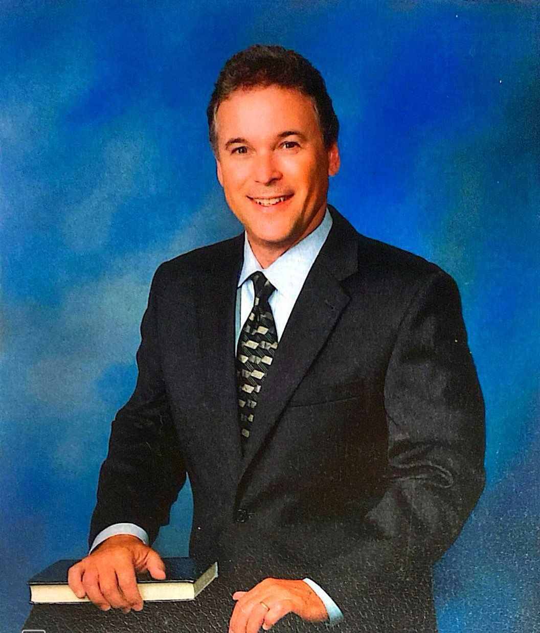 A man in a suit and tie is holding a bible