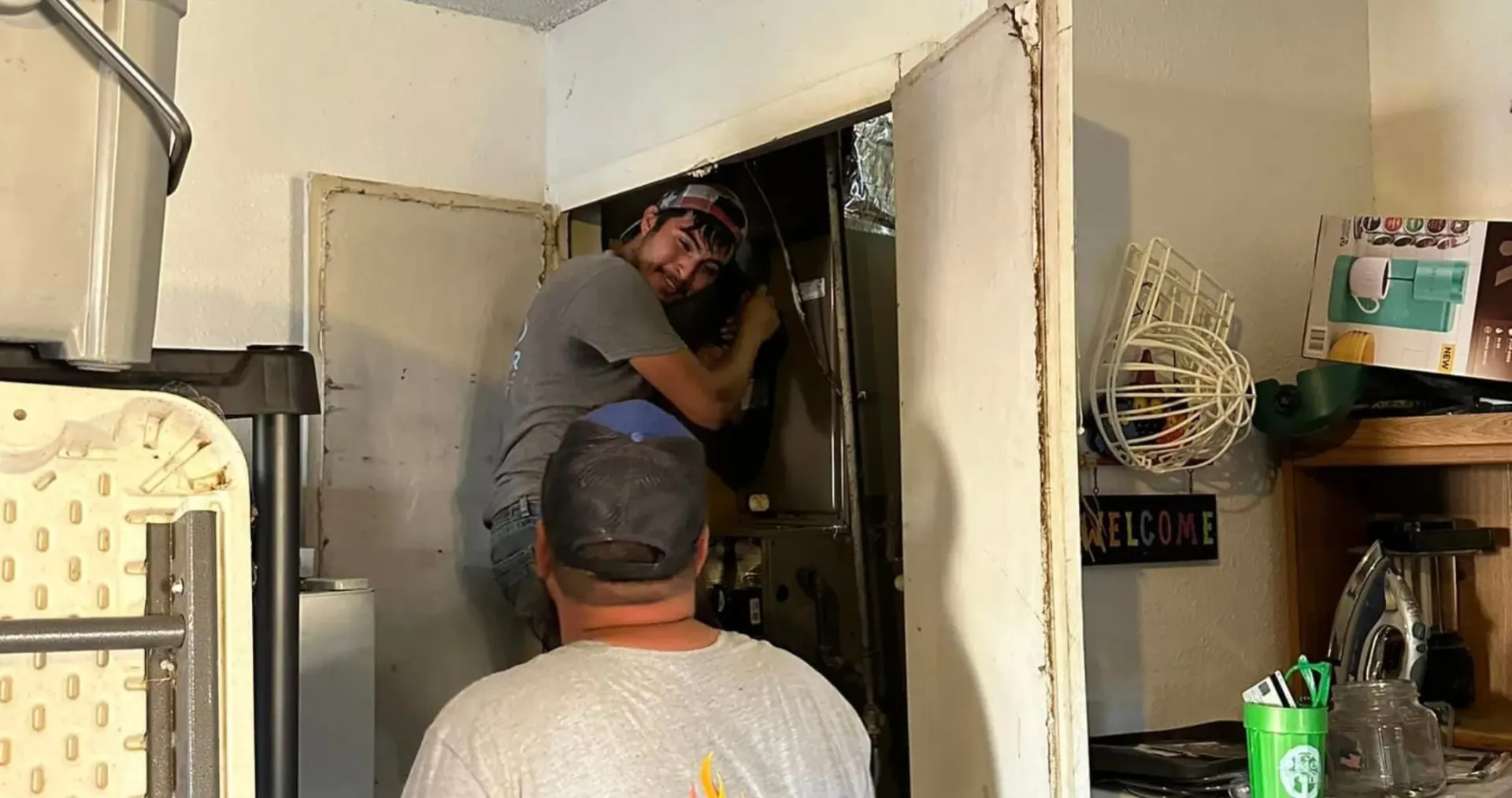 Air Fair Heat and Air LLC - Two men are working on a refrigerator in a kitchen.