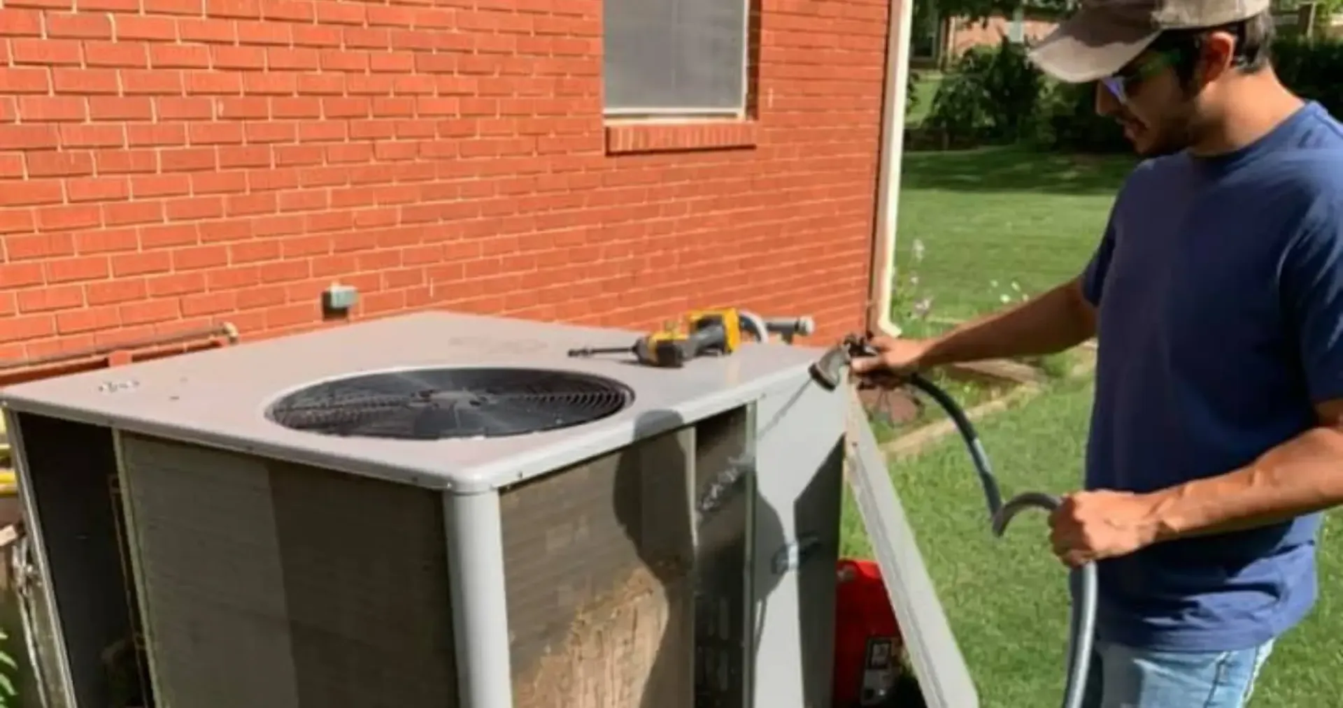 Air Fair Heat and Air LLC - A man is working on an air conditioner outside of a brick building.