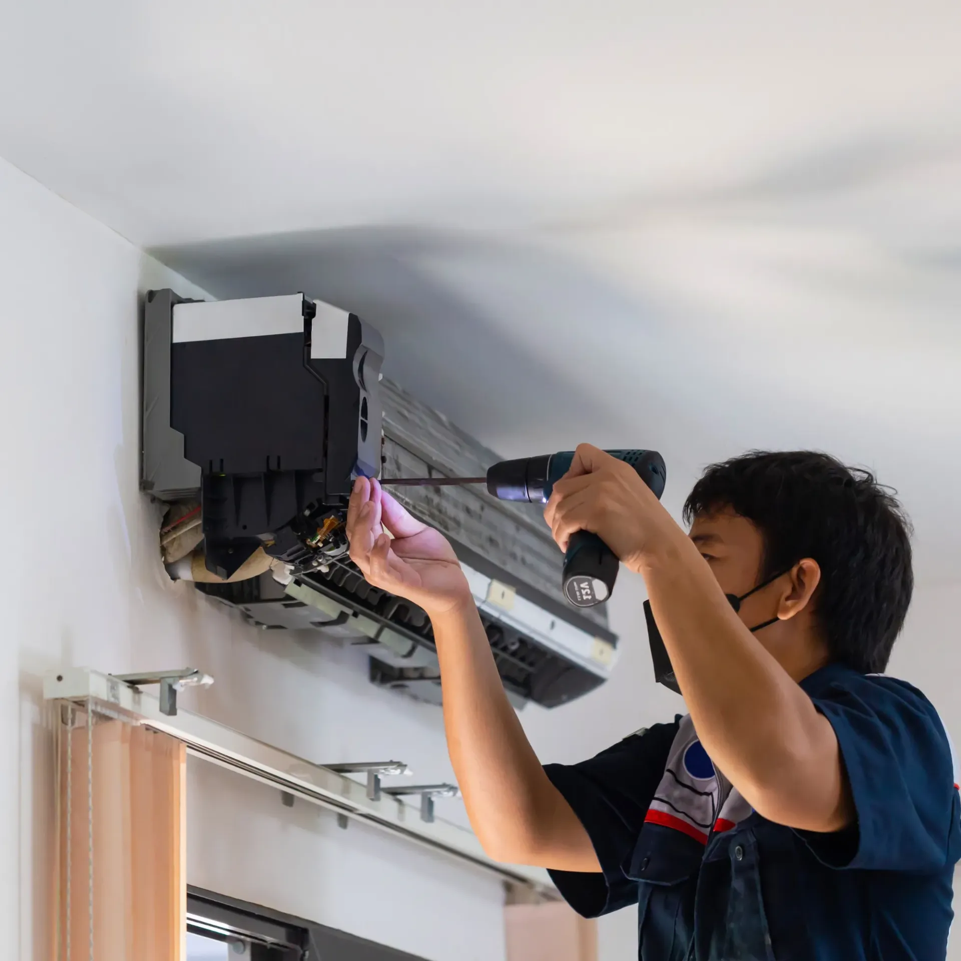 Air Fair Heat and Air LLC - A man is using a drill to fix an air conditioner.
