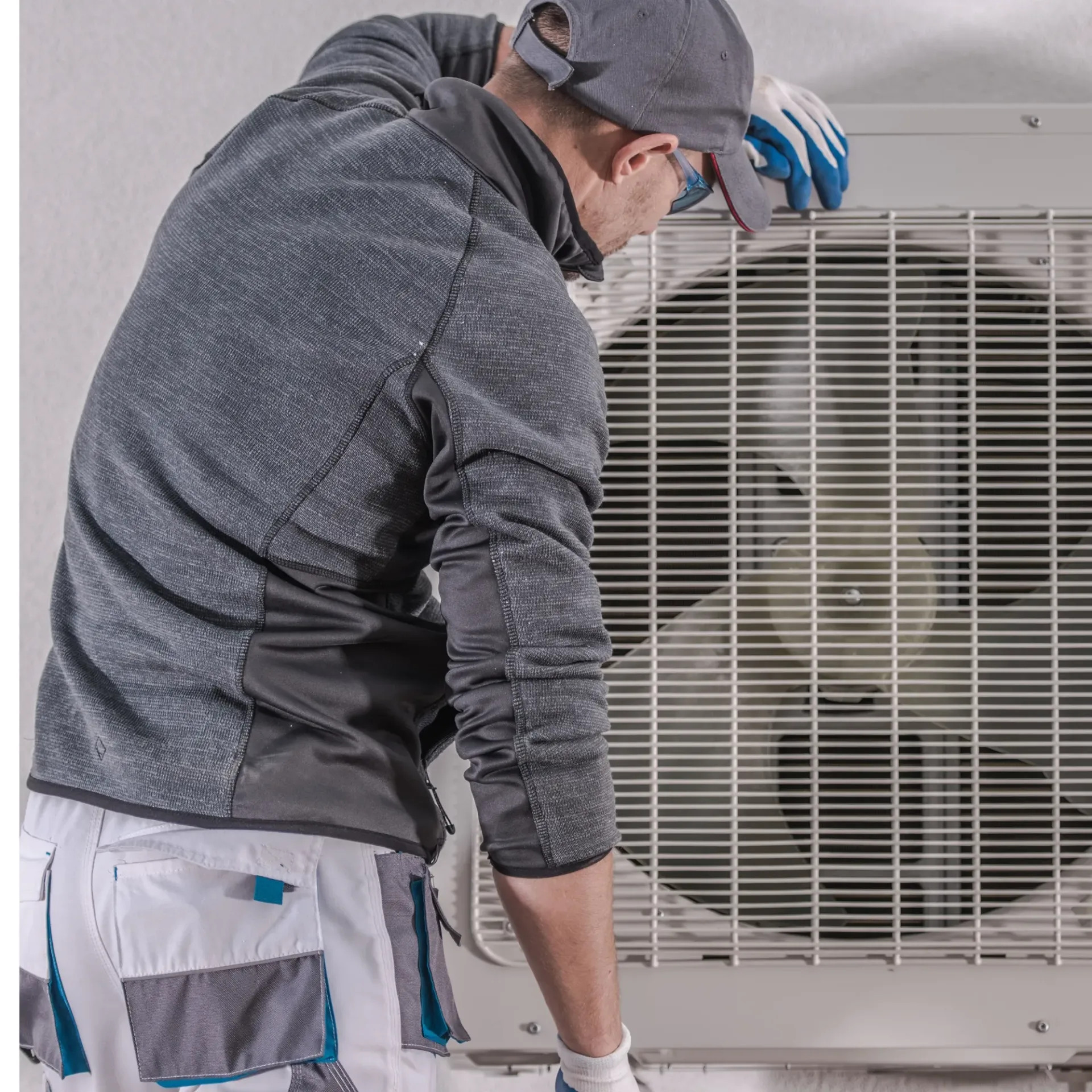 Air Fair Heat and Air LLC - A man wearing a hat and gloves is working on an air conditioner.
