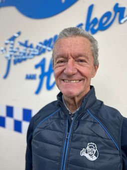 Een man in een wit overhemd lacht voor de camera