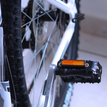 Een close-up van een fietspedaal met een oranje reflector