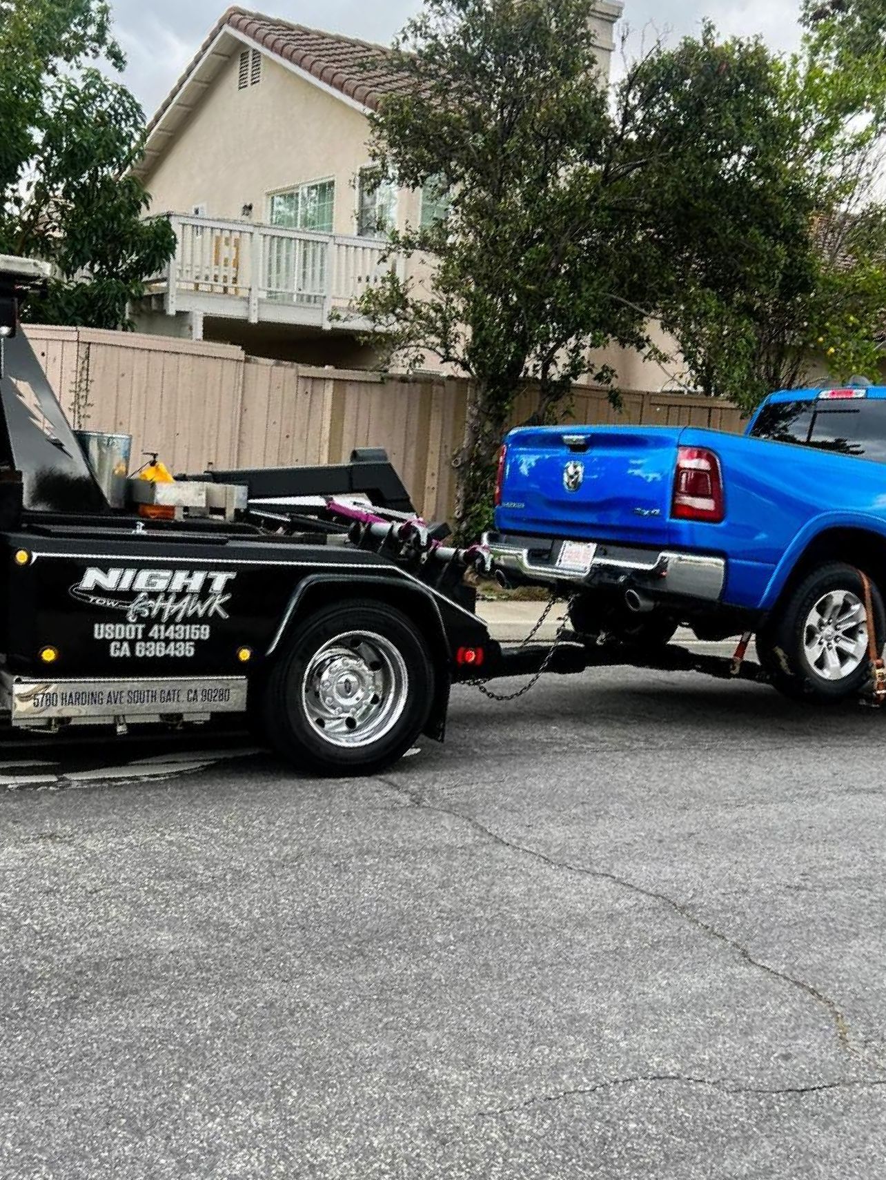 A blue truck is being towed by a tow truck.
