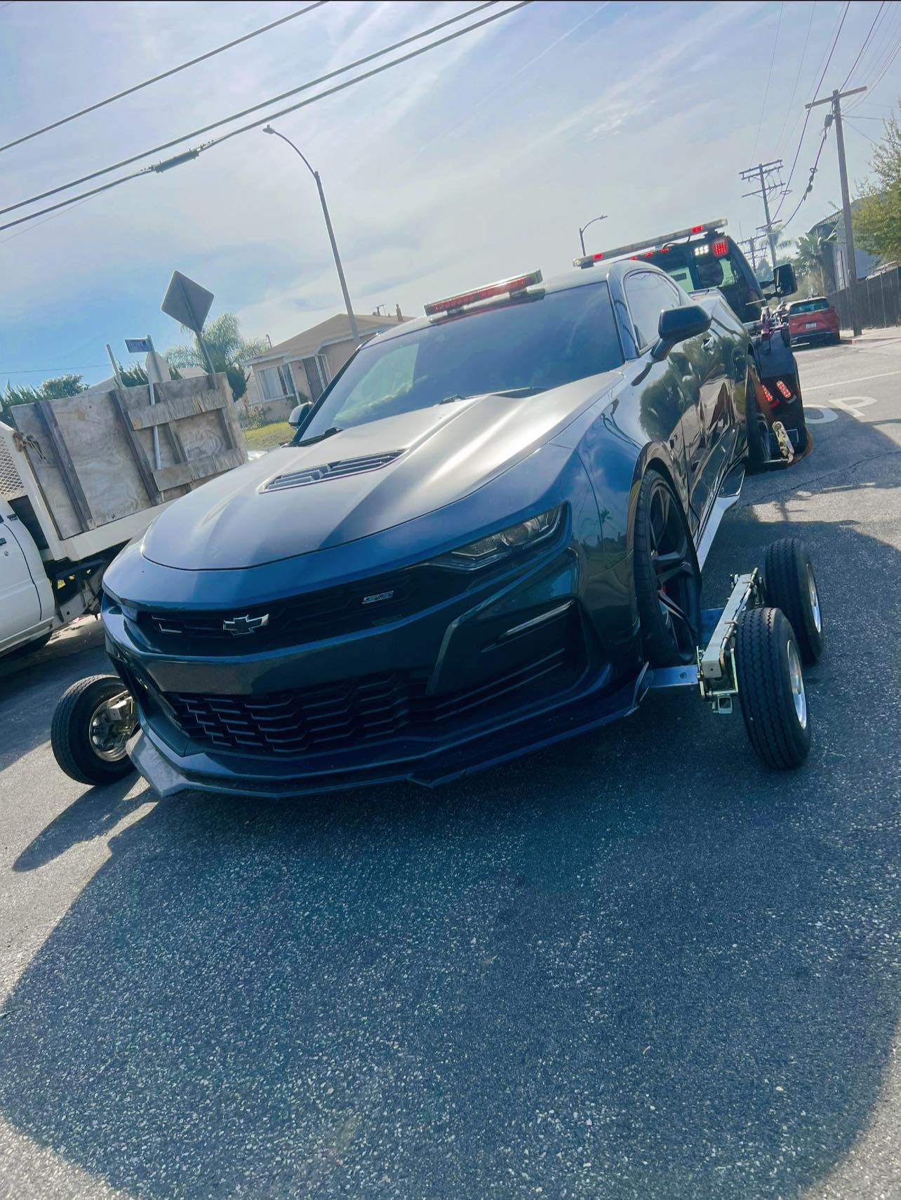 Black motorcycle strapped to a tow truck at night, parked near a dealership.