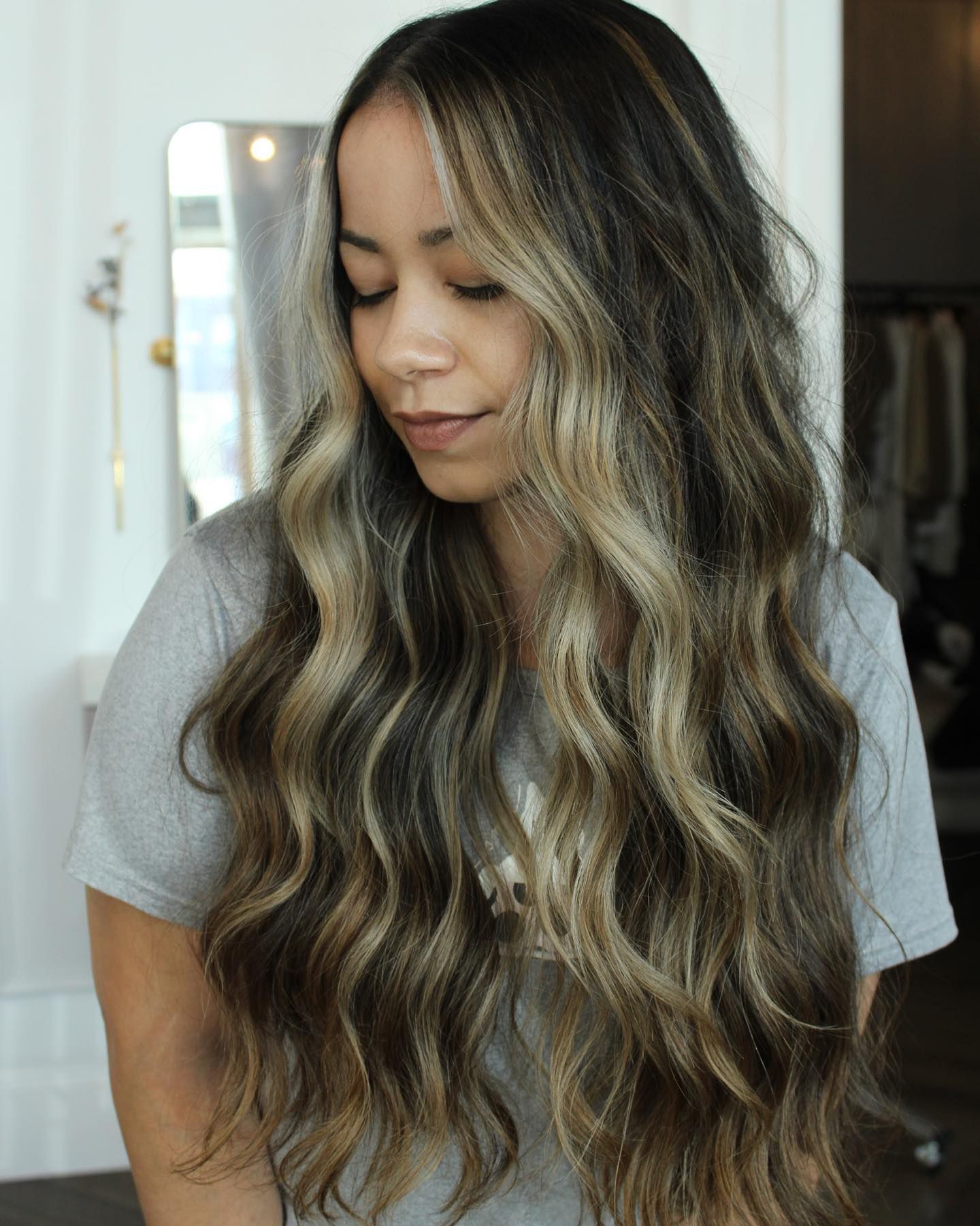 a woman with long wavy hair is wearing a gray shirt .