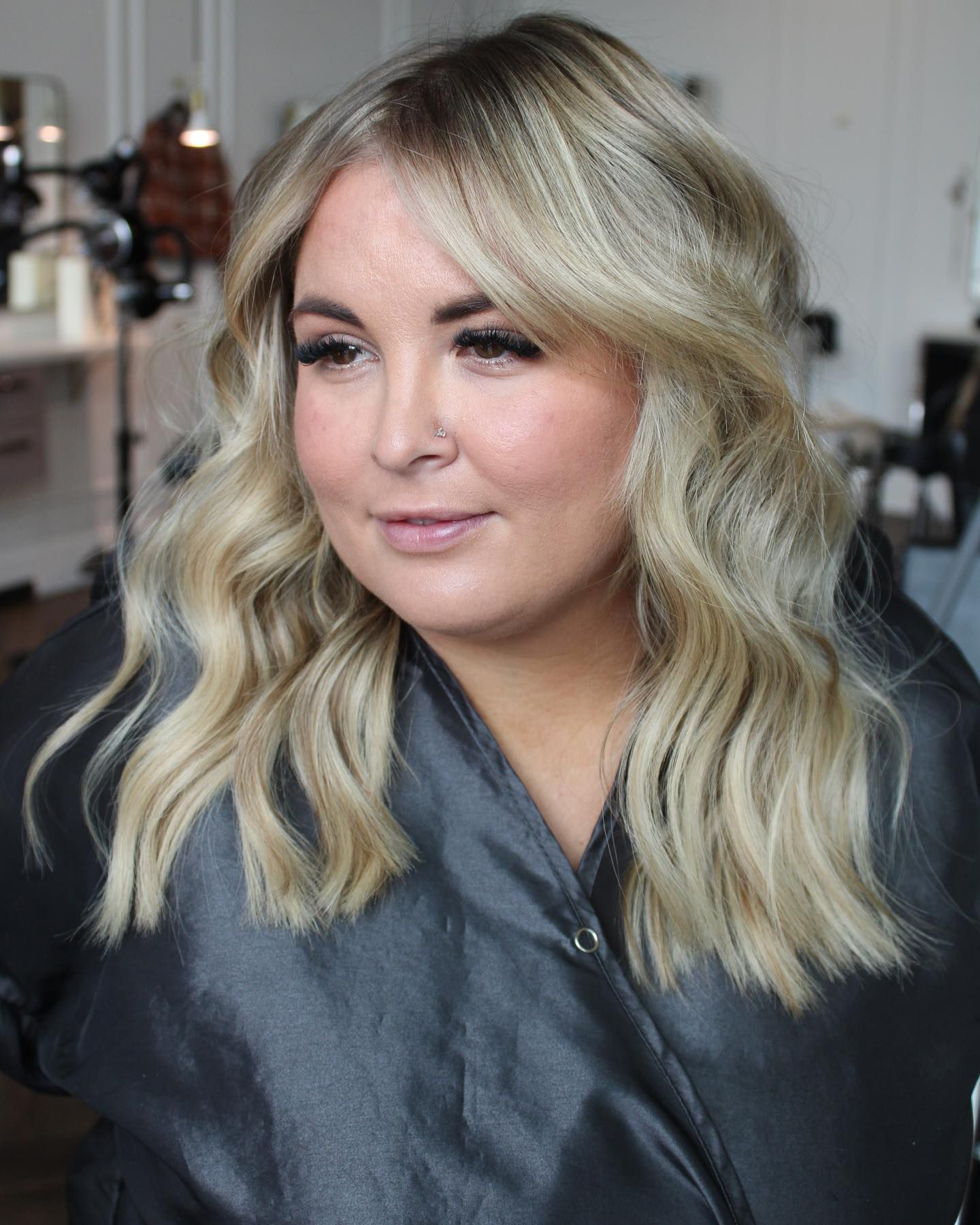 a woman with blonde hair and a nose ring is sitting in a chair .