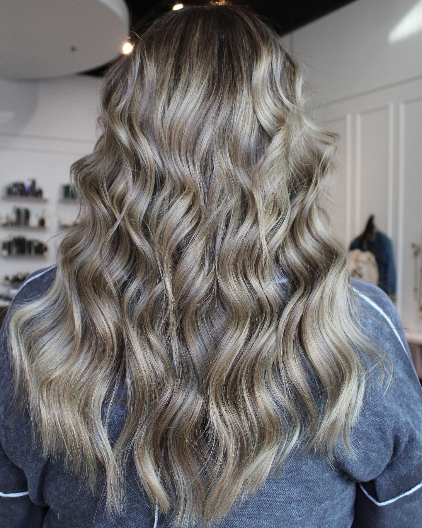 a woman with long wavy hair is wearing a gray sweater .