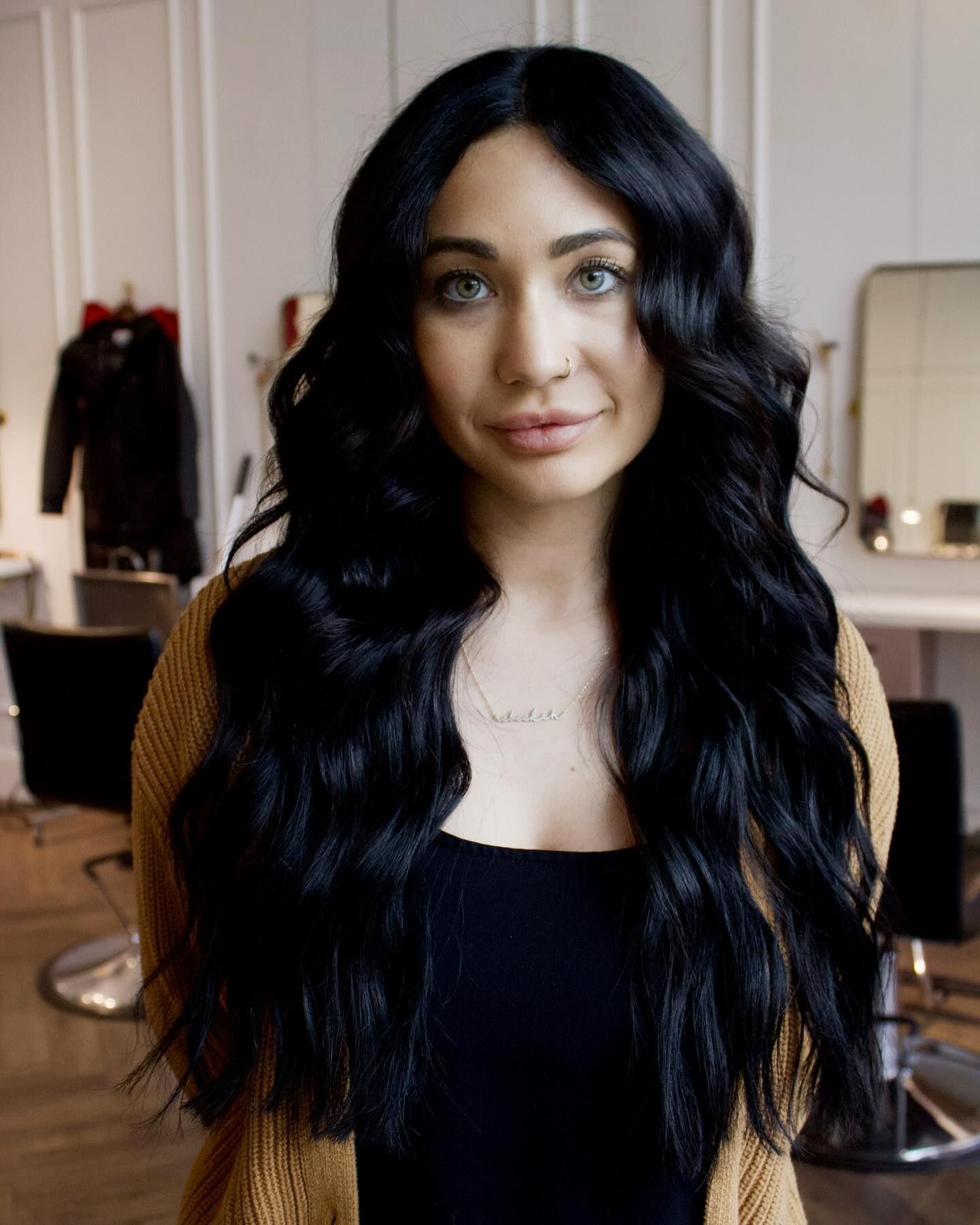 a woman with long black hair is standing in a salon .