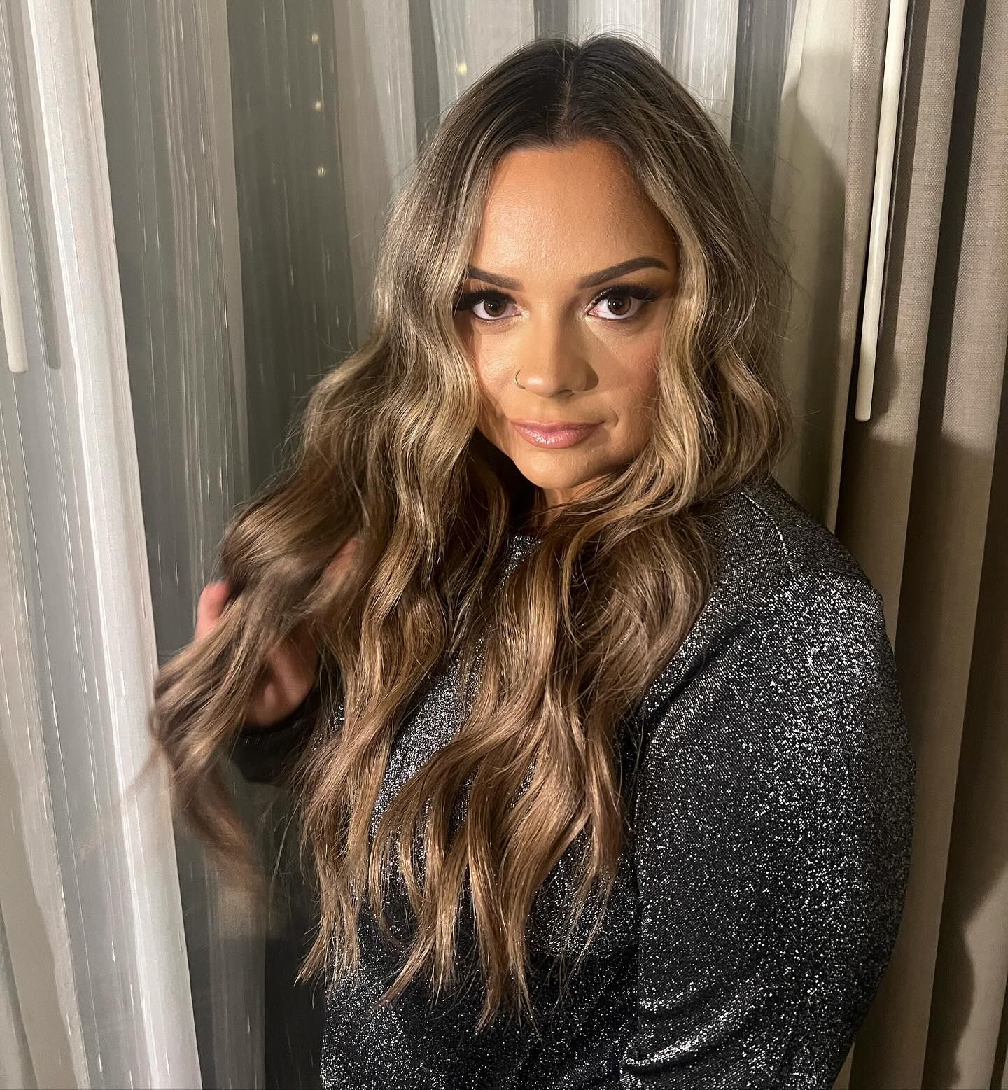 a woman with long hair is standing in front of a window .