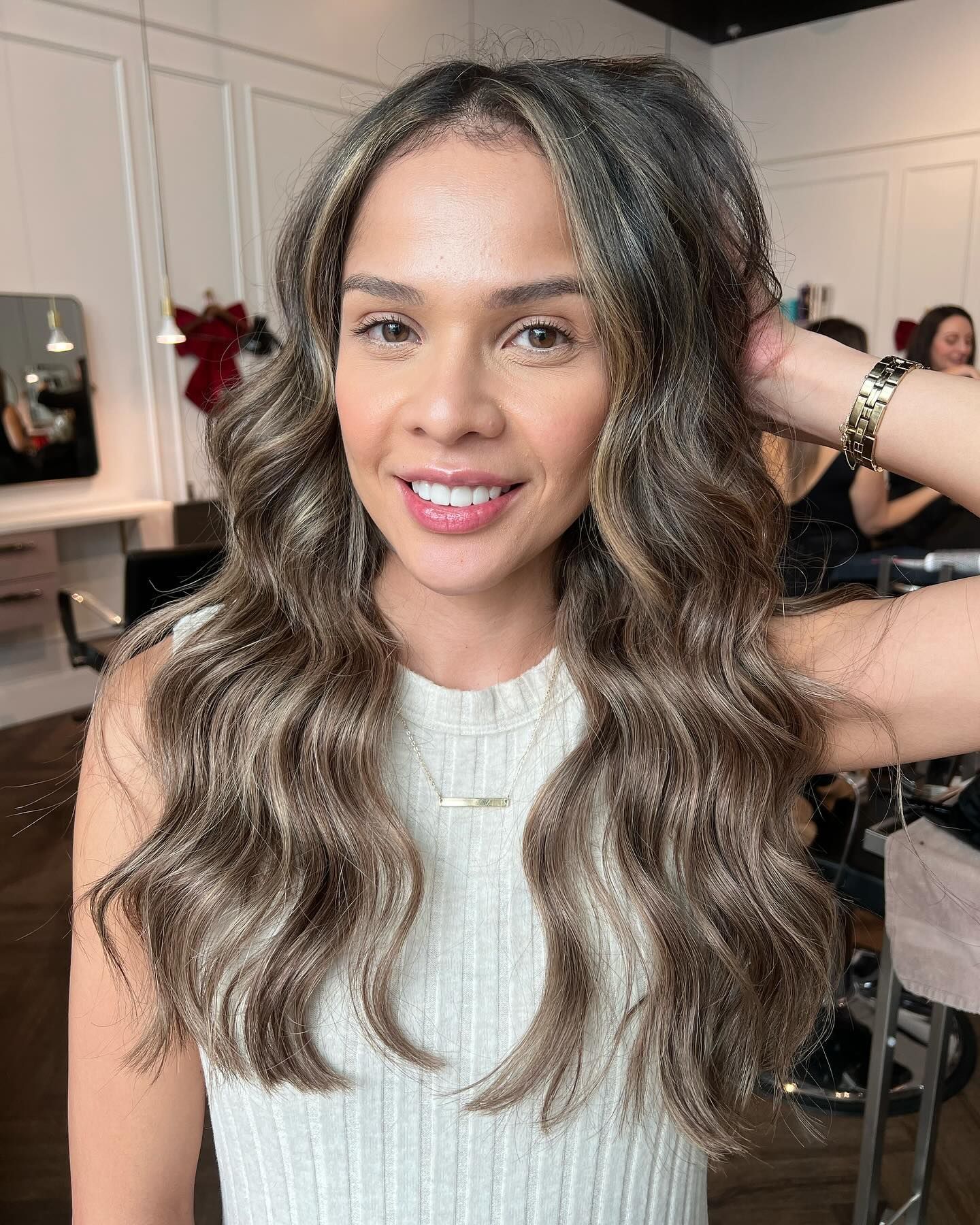 a woman with long brown hair is smiling in a salon .