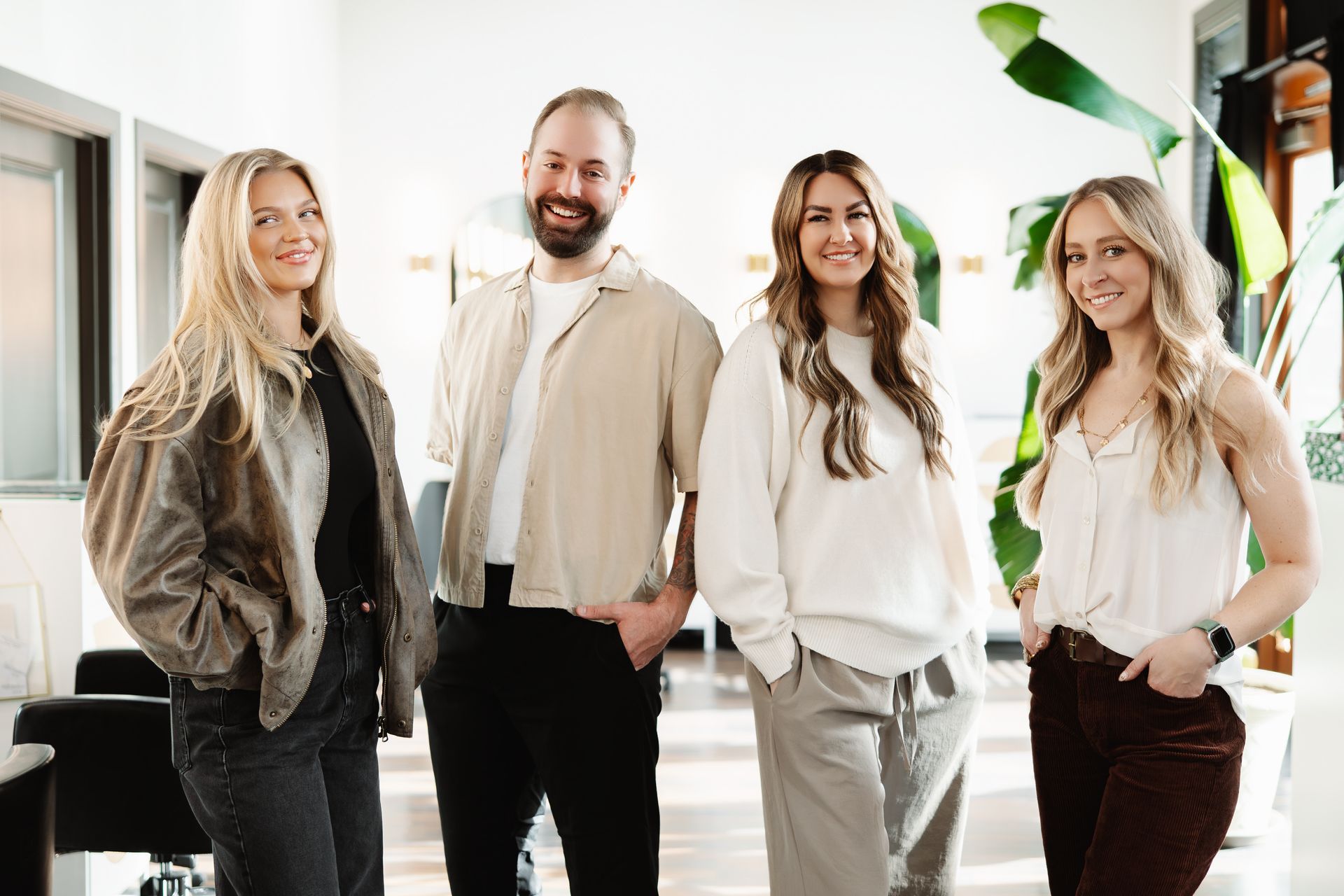 a woman wearing a white shirt and black jeans stands in front of a pink wall