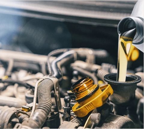 Fresh motor oil being poured into a car engine during an oil change.