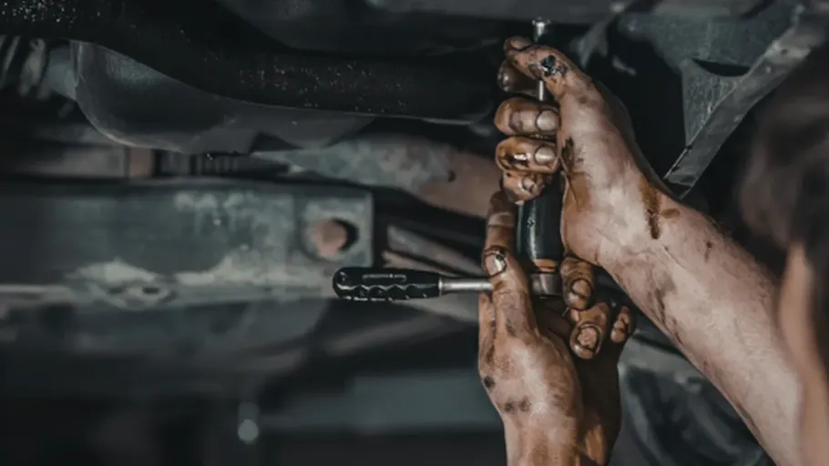 Mechanic working on the undercarriage of a car for on-site repair.
