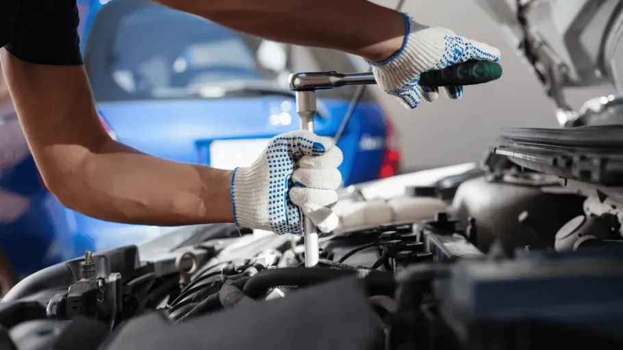 Mechanic using a socket wrench to repair a car engine part.
