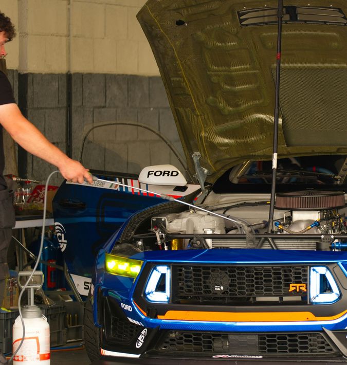 Professional mechanic in a jumpsuit working on a vehicle in a garage.