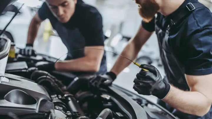 Two mechanics inspecting a car engine in a professional auto shop.