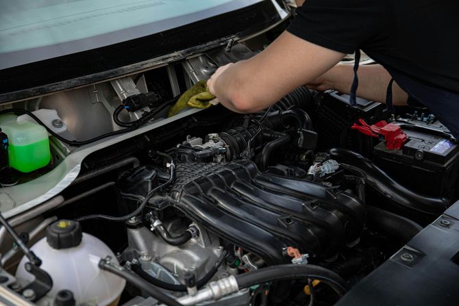 Close-up of a mechanic checking the oil dipstick of a vehicle engine.