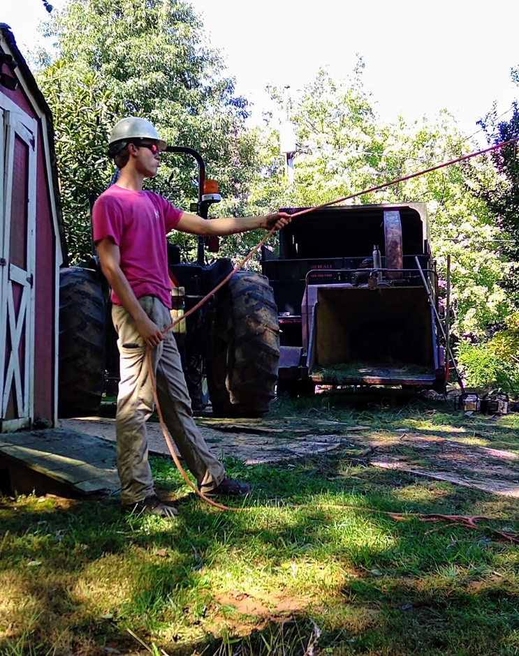 A man in a pink shirt is standing in front of a tractor.