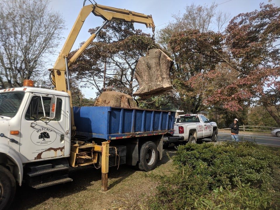 A dump truck with a crane attached to it is carrying a large rock.
