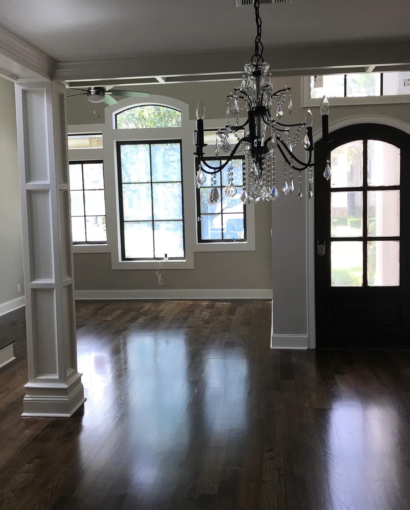 A living room with hardwood floors and a chandelier hanging from the ceiling.