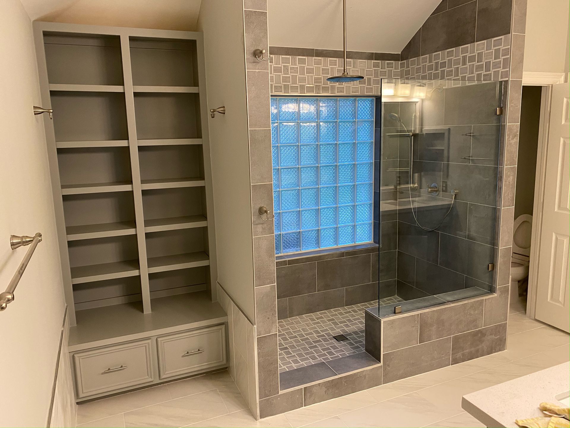 A bathroom with a walk in shower and shelves.