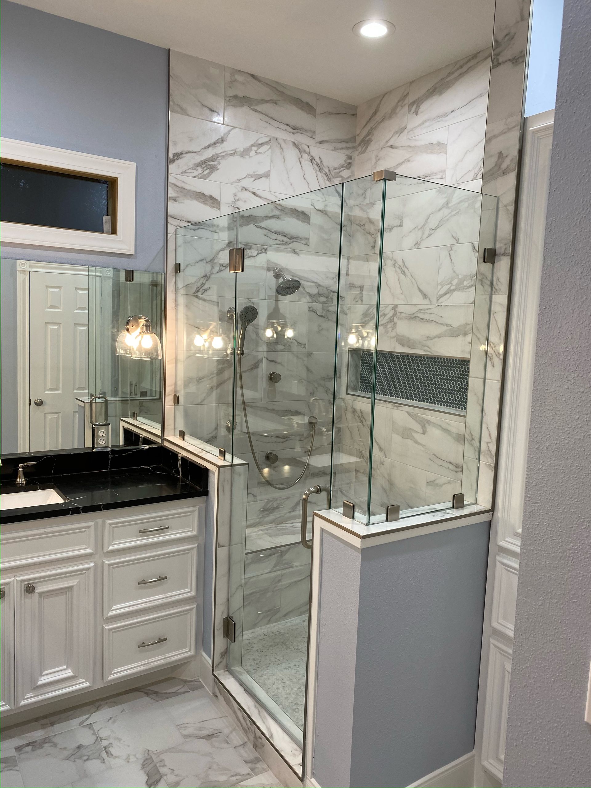 A bathroom with a walk in shower , sink and mirror.
