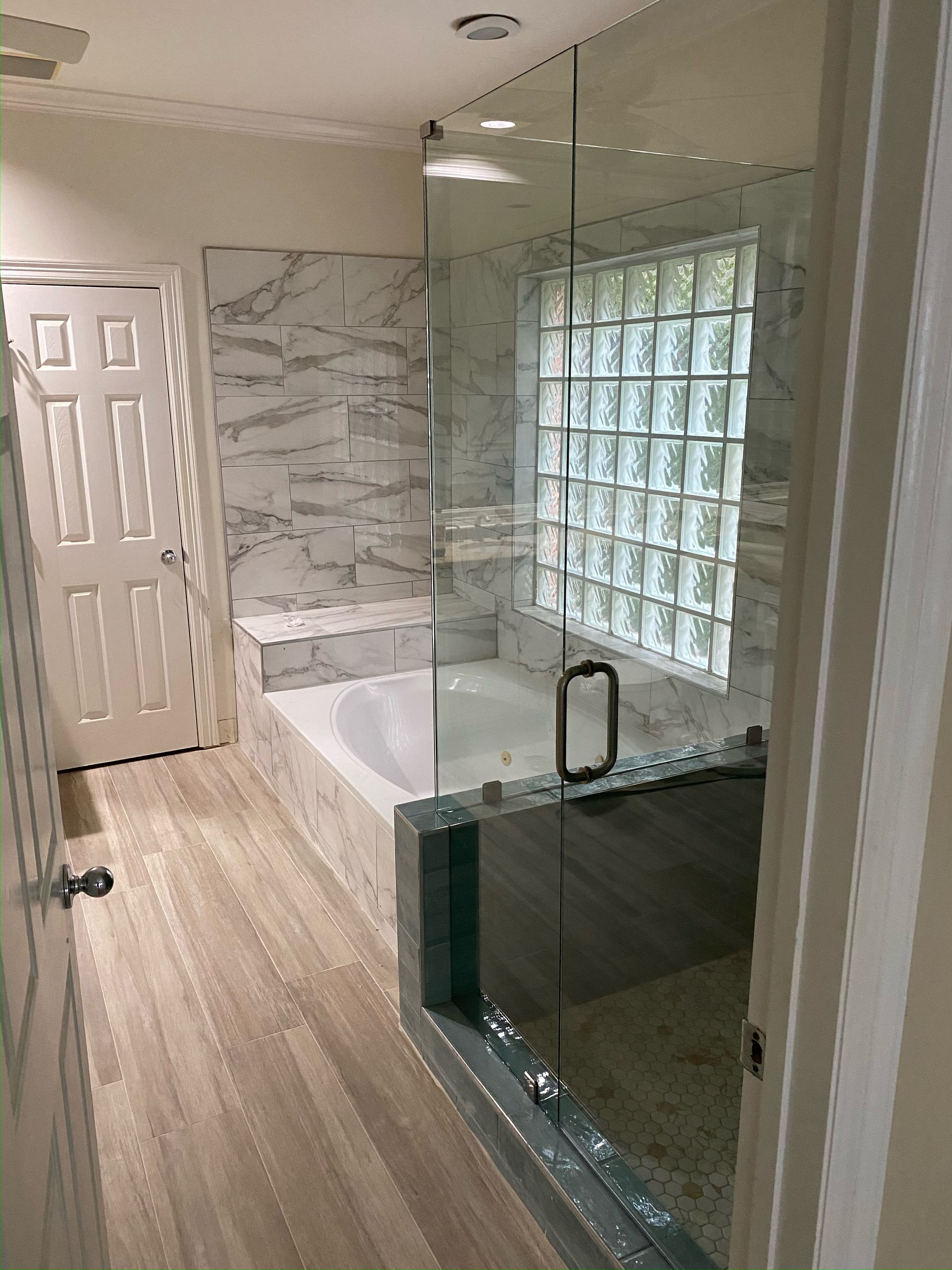 A bathroom with a bathtub and a glass shower door.