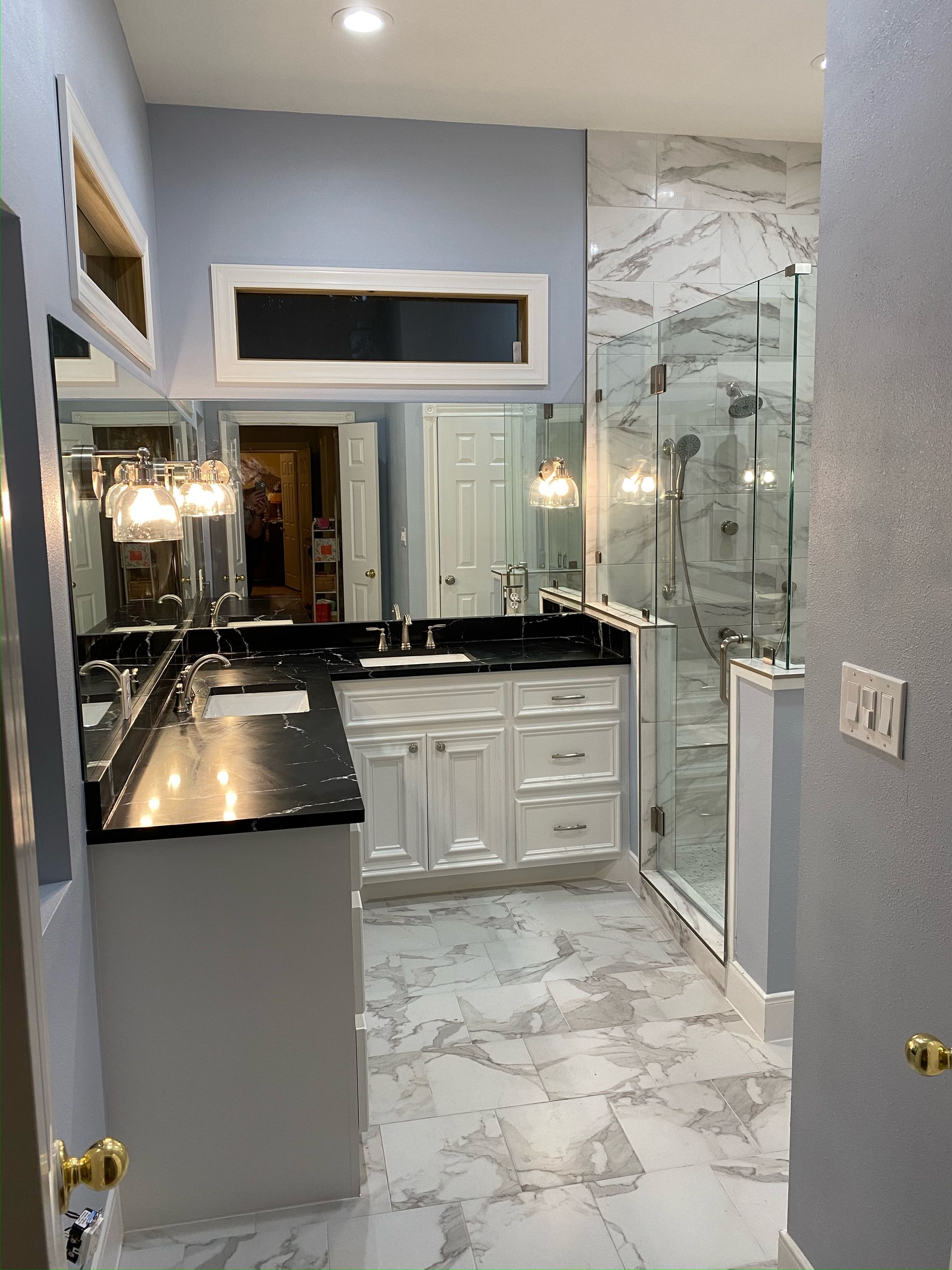 A bathroom with two sinks and a walk in shower.
