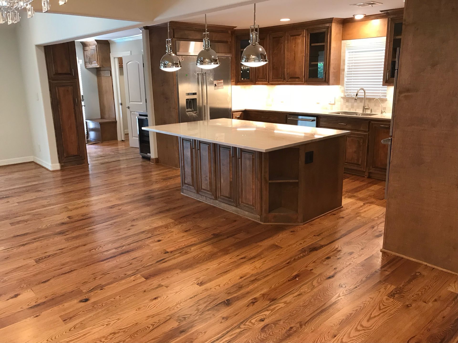 A kitchen with hardwood floors and a large island in the middle.