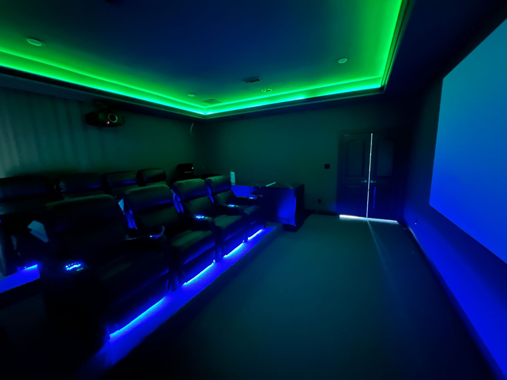 A home theater with blue and green lights on the ceiling.