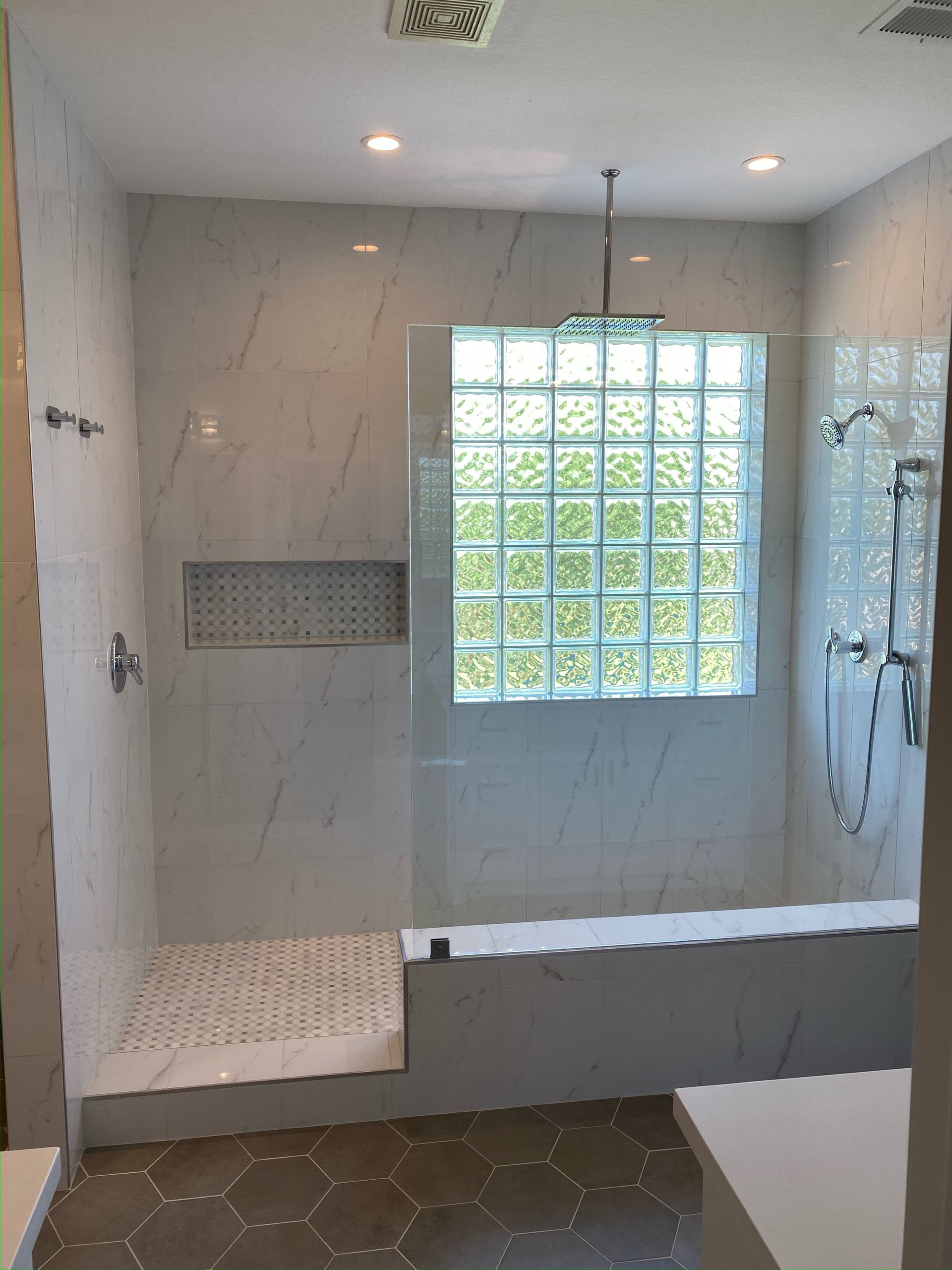 A bathroom with a walk in shower and a window.