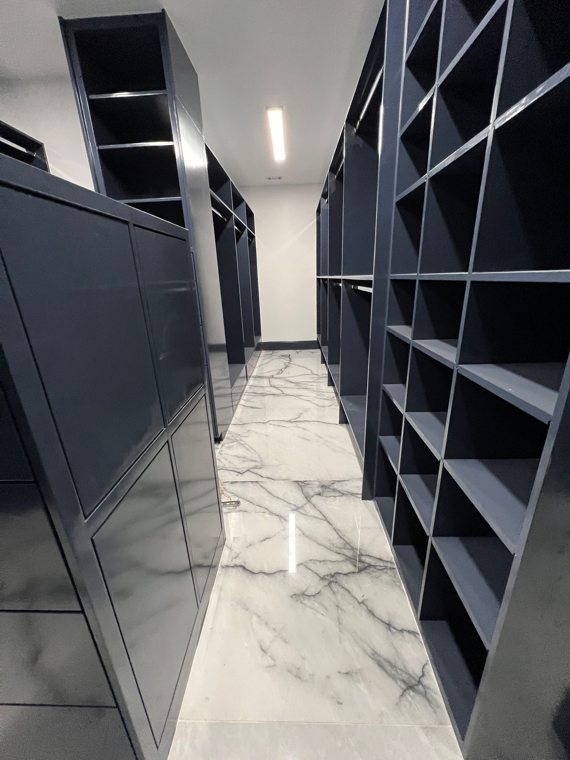 A hallway with lots of shelves and a marble floor