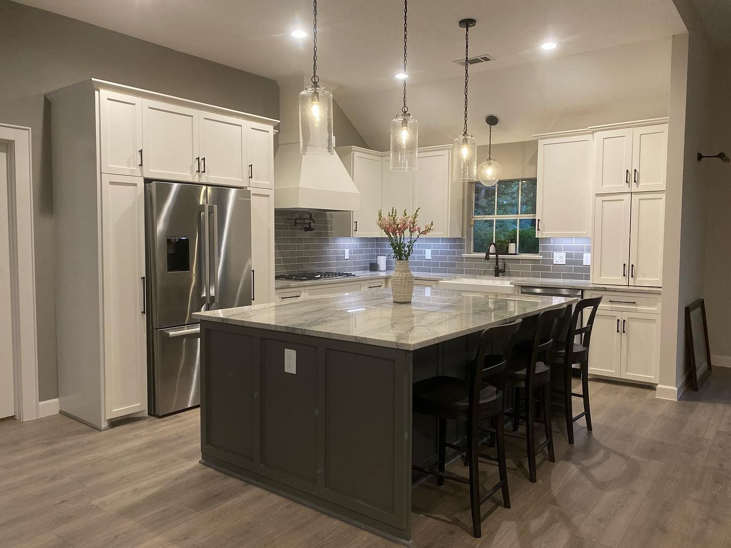 A kitchen with white cabinets , stainless steel appliances , and a large island.
