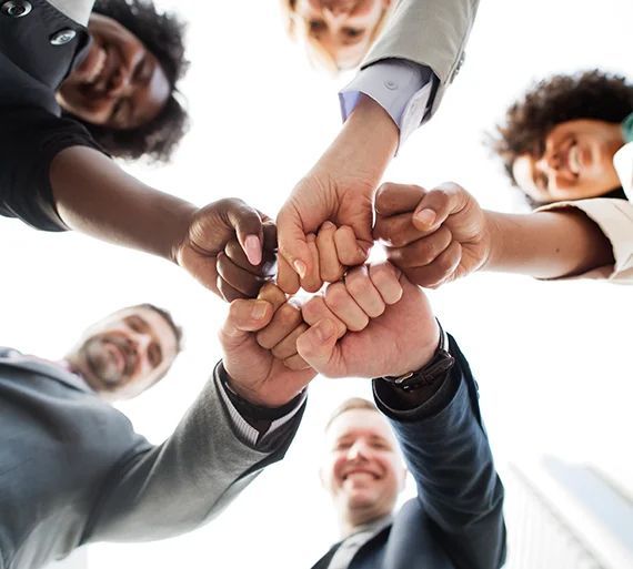 A group of people putting their fists together in a circle.