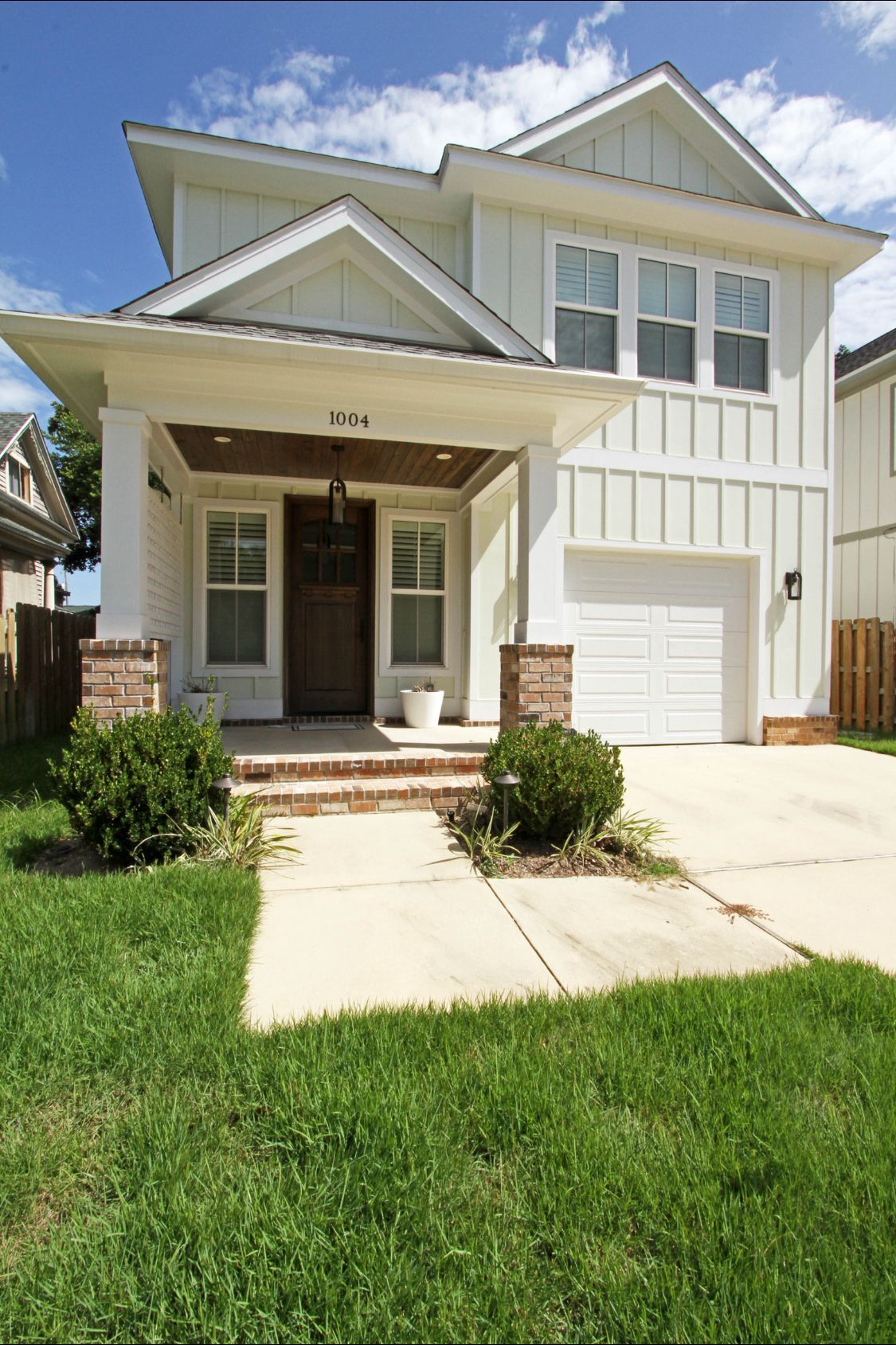 A white house with a white garage door is sitting on top of a lush green lawn.