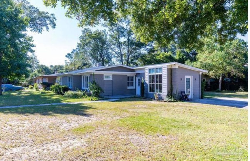 A house with a lot of windows and a lot of grass in front of it.