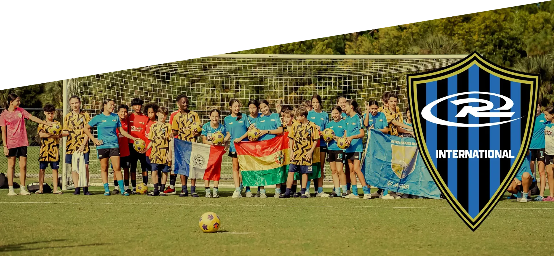 Group of smiling girls in blue soccer jerseys, with team logo, possibly soccer team photo.